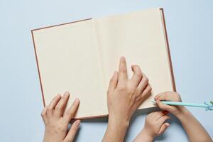 verhalenboek concept met kind hand- Holding Open boek Aan blauw achtergrond foto