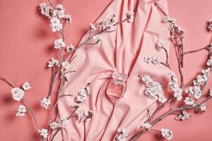 een roze kleding stof met bloemen en een fles van parfum foto