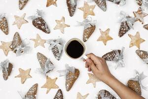 een hand- Holding een kop van koffie omringd door Kerstmis decoraties foto