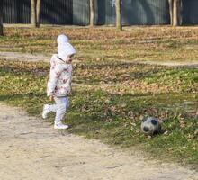 de kind is spelen met de bal. een weinig vier jaar oud meisje Toneelstukken met een Amerikaans voetbal. foto