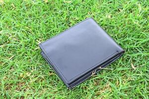 een zwart portemonnee houdende Aan de gras foto