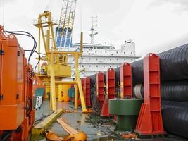 de dek leggen schuit. pijpen en hijs- kranen Aan de schip. uitrusting voor houdende een pijpleiding Aan de zeebedding foto