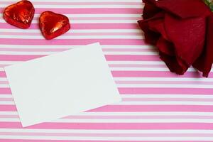 valentijnsdag dag kaart met roos en chocolaatjes roze en wit achtergrond foto