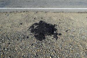 de stuk van vers asfalt welke liet vallen uit Aan een langs de weg foto