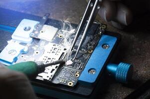 top visie, monteur aan het doen reparaties smartphone moederbord, smartphone reparatie, stroomkring reparatie foto