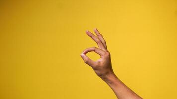 man's hand- shows Oke gebaar of alles is prima Aan een geel achtergrond foto
