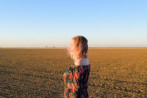 vrouw in een geploegd veld- in een rood Zwart jurk Aan een zonsondergang achtergrond. foto