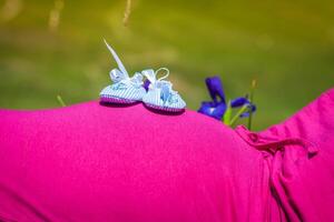 zwanger vrouw aan het liegen Aan een gras met baby schoenen Aan haar buik foto