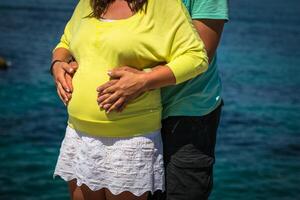 zwanger vrouw en haar man Holding haar handen Aan haar baby buil foto