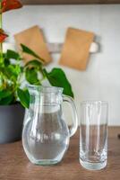 kruik met Doorzichtig verkoudheid water Aan keuken tafel in de huis foto