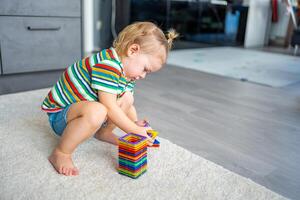 weinig meisje spelen kleurrijk magneet plastic blokken uitrusting Bij huis. de kind spelen leerzaam spellen. vroeg kinderjaren ontwikkeling. foto