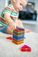 weinig meisje spelen kleurrijk magneet plastic blokken uitrusting Bij huis. de kind spelen leerzaam spellen. vroeg kinderjaren ontwikkeling. foto