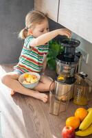 weinig meisje maken vers sap zittend Aan de tafel in huis keuken foto