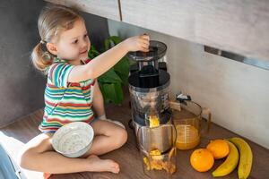 weinig meisje maken vers sap zittend Aan de tafel in huis keuken foto