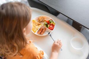 weinig meisje hebben een evenwichtig ontbijt in huis keuken in de ochtend- foto