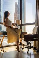 elegant zakenvrouw freelancer werken met laptop en zittend Aan tafel, genieten van panoramisch visie in de stad achtergrond. laag sleutel foto. hoog kwaliteit foto