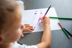 weinig meisje trekt met gekleurde potloden in huis. foto