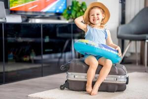 weinig meisje met koffer bagage bagage en opblaasbaar leven boei klaar naar Gaan voor op reis Aan vakantie foto