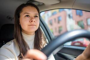 gelukkig vrouw het rijden een auto en lachend. schattig jong succes gelukkig brunette vrouw is het rijden een auto. portret van gelukkig vrouw bestuurder stuurinrichting auto. foto