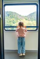 mooi weinig meisje op zoek uit trein venster buiten, terwijl het in beweging. op reis door spoorweg, Europa foto