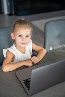 weinig meisje leerling online aan het leren, klasse studie online video telefoontje met leraar Aan de laptop huis. afstand aan het leren concept. foto