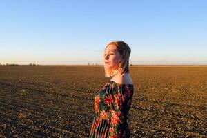 vrouw in een geploegd veld- in een rood Zwart jurk Aan een zonsondergang achtergrond. foto