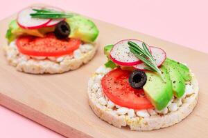 rijst- taart boterhammen met avocado, tomaat, huisje kaas, olijven en radijs Aan houten snijdend bord. gemakkelijk ontbijt. eetpatroon voedsel. snel en gezond boterhammen. knäckebröd met smakelijk vulling foto