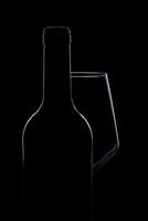 silhouet van wijn glas fles vol van rook in zwart achtergrond foto