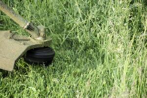 toepassing trimmers. gras maaien groen gras gebruik makend van een visvangst lijn trimmer foto