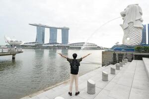 Mens in merlion fontein in voorkant van de jachthaven baai foto