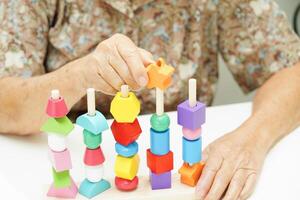 Aziatisch ouderen vrouw spelen puzzels spel voor behandeling Dementie het voorkomen en alzheimer ziekte. foto