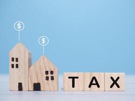 miniatuur huis en houten blokken met de woord belasting. de concept van betaling belasting voor huis, eigendom investering, huis hypotheek, echt landgoed foto