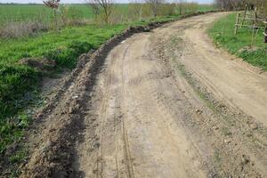 aarde weg geëgaliseerd door een nivelleermachine. weg in dorp foto