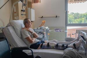 een Mens met een gebroken been in een orthese Aan een bed in een kliniek na een ongeluk en een breuk van de dijbeen foto