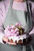 een vrouw siert een eigengemaakt Pasen taart met roze sakura bloemen, lente bloesem foto