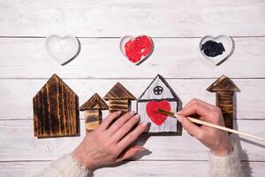 vrouw handen trek een hart Aan een houten huis, stap door stap doe-het-zelf, knutselen zoet huis foto