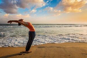 vrouw aan het doen yoga zon begroeting surya namaskar foto