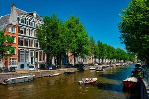 Amsterdam kanaal met toerist boot en oud huizen foto