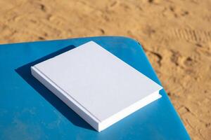 blanco boek mockup Aan lounge Aan zanderig strand foto