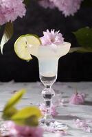 voorjaar nog steeds leven met een glas van verkoudheid margarita met limoen, roze sakura bloemen foto
