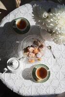 Engels stijl thee pauze, nog steeds leven met bloemen en donuts in de ochtend- zon foto