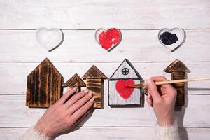 vrouw handen trek een hart Aan een houten huis, stap door stap doe-het-zelf, knutselen zoet huis foto