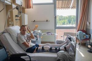 een Mens met een gebroken been in een orthese Aan een bed in een kliniek na een ongeluk en een breuk van de dijbeen foto