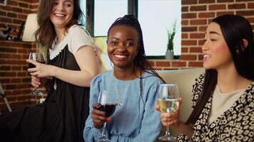 multi-etnisch vrienden hebben innemend gesprek gedurende verjaardag partij in knus appartement. bipoc groep van mensen chatten in leven kamer, aan het eten snacks en drinken alcohol foto