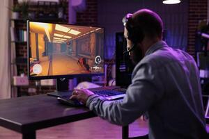 ervaren gamer concurrerende in intens online multiplayer videogame, omroep esports toernooi leven van steen muur appartement. Mens gebruik makend van deskundige niveau gaming muis en toetsenbord, voorkomen invoer vertraging foto