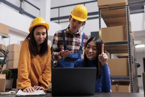 Aziatisch levering onderhoud managers analyseren logistiek Aan laptop terwijl staand in de buurt bureau in magazijn. pakhuis pakket afhandelaars en Verzending operator op zoek Bij bestellingen checklist Aan computer foto