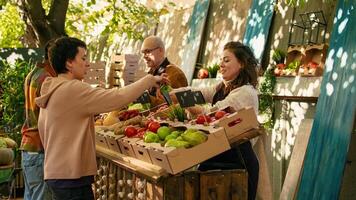 jong verkoper geven vrij appel monsters naar klanten, hebben pret met vers producten bemonstering Bij lokaal groenmarkt. vrouw snijdend plakjes van fruit naar geven naar klanten, klein bedrijf baasje. foto