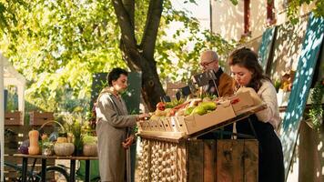 mannetje koerier draag- rugzak en aan het wachten voor produceren bestellen Bij lokaal straat boeren markt. boeren leveren natuurlijk biologisch fruit en groenten naar klanten, postbode Aan fiets met helm. foto