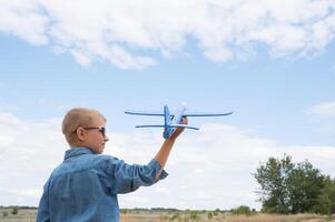 achterzijde visie van een kind jongen met een vliegtuig dromen van op reis in de zomer in natuur Aan een zonnig dag foto