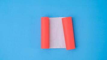 een oranje gerold plein papier is verspreiding uit in een blanco wit vel Aan een licht blauw achtergrond. verfrommeld blanco wit papier met kopiëren ruimte voor tekst of reclame ruimte. foto